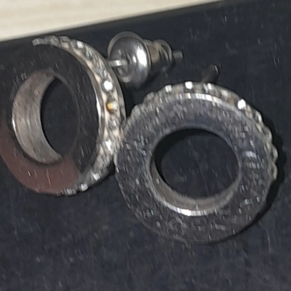 Edblad Snygga runda örhängen med en kombination av silver och svart. De har en modern design med en cirkulär form och en stilren look. Perfekta för att ge en elegant touch till din outfit.. Asusteet.