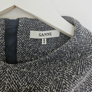 Grå klänning från Ganni - Snygg grå klänning från Ganni i en stilren design. Klänningen har trekvartsärmar och en normal passform, perfekt för en chic look. Materialet är en blandning av polyester och bomull vilket ger en bekväm känsla.