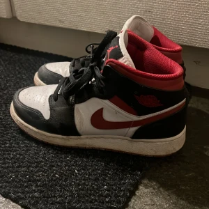 Nike Air Jordans i svart, vitt och rött - Säljer ett par klassiska Nike Air Jordans i svart, vitt och rött. Jordan 1 mid. Kan såklart tvättas upp lite innan postningen. Stl 39, hela skon är super skick!
