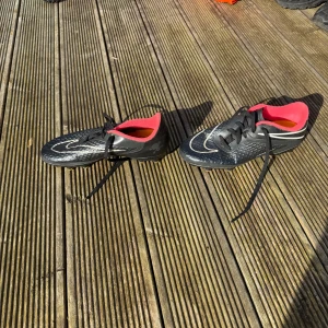 Nike hyper venom OG - Snygga svarta fotbollsskor från Nike med vita detaljer och en röd insida. Skorna har snörning och en modern design som passar perfekt för fotbollsplanen.