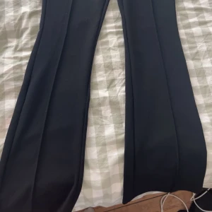 Svarta vida byxor - Snygga svarta byxor med hög midja och vida ben. Perfekta för en stilren look. De har en elegant passform som ger en modern touch.