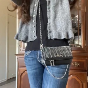 Svart axelväska från Zadig & Voltaire Rock Nano Dotted Swiss Clutch - Helt nytt & oanvänd, snygg svart axelväska från Zadig & Voltaire med silverfärgade nitar och en kedja som axelrem. Originala priset 3600kr!! Och säljer den för 1900kr. Btw säljer den för jag hade köpt fel.