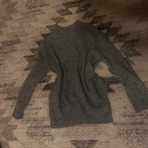Grå stickad tröja - Säljer en mysig grå stickad tröja med lång ärm och ribbad struktur. Perfekt för kyliga dagar och enkel att matcha med olika outfits. Tröjan har en klassisk design med rund hals och är i storlek XS.
