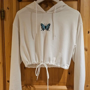 Vit croppad hoodie - Fin vit croppad lite tunnare hoodie med justerbar dragsko i nederkanten. Sparsamt använd🦋