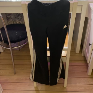 Svarta träningsbyxor från Adidas - Snygga svarta träningsbyxor från Adidas med de klassiska tre vita ränderna längs sidorna. Byxorna har en bootcut-stil och är perfekta för en sportig look. Adidas-loggan är tydligt synlig på sidan.Pris kan absolut diskuteras 🤗och fler bilder 💕säljer dom då dom är för små🔥