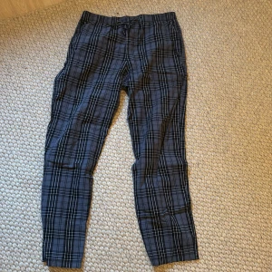 Blåa rutiga pyjamasbyxor med snörning H&M - Snygga blåa byxor med rutig design och snörning i midjan. Perfekta för en stilren look med en touch av mönster. Passar bra till både vardag och mer uppklädda tillfällen.
