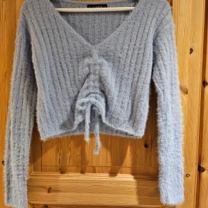 Ljusblå fluffig tröja från Zaful - Mysig ljusblå tröja från Zaful med en fluffig textur och ribbad design. Tröjan har en v-ringad hals och knytning framtill som ger en snygg detalj. 