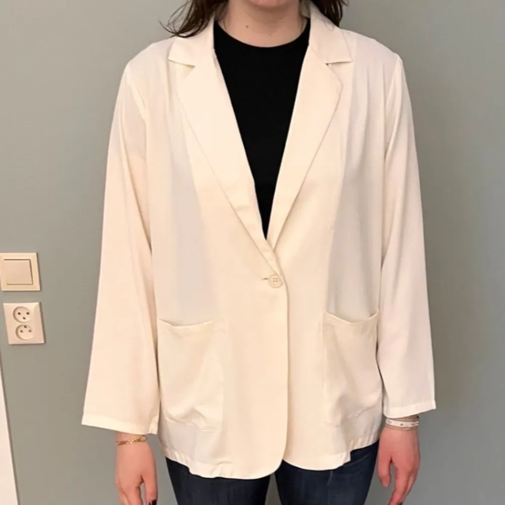 Säljer en stilren vit kavaj från BikBok. Kavajen har en klassisk design med långa ärmar och knäppning framtill. Materialet liknar en blus. Perfekt för en chic look. . Puvut & Bleiserit.