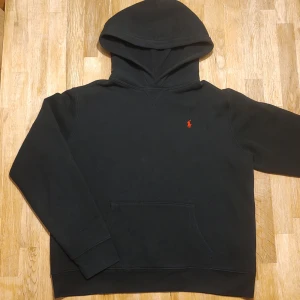 Svart hoodie från Ralph Lauren - Klassisk hoodie från Ralph Lauren. Stl XL=18-20, ganska bred modell, sitter ungefär som en vuxen XS/S. Fint skick men har en lagning på fickan, syns knappt, se bild. Därav superpris! Fråga gärna om mått etc ✨