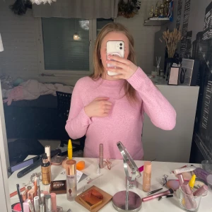 Rosa stickad tröja - Säljer en söt rosa stickad tröja med långa ärmar och ribbade muddar. Perfekt för kyligare dagar och ger en mysig känsla. Tröjan har en enkel design som är lätt att matcha med olika outfits. Finns ett litet hål i ärmen men det går lätt att fixa.