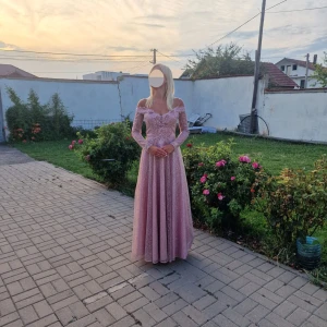 Balklänning/galaklänning  - Elegant rosa långklänning med offshoulder-design och vackra spetsdetaljer. Klänningen har pärlor och blommiga broderier som ger en lyxig känsla. Perfekt för speciella tillfällen.