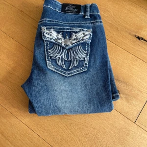 Blå jeans med broderade fickor - Snygga blå jeans från Love Indigo med unika broderade detaljer på bakfickorna. Jeansen har en klassisk femficksdesign och en bekväm passform. Perfekta för dig som vill ha något extra i garderoben!