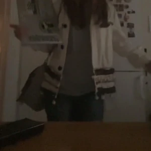 Beige cardigan jacka med fransar - Säljer en beige cardigan jacka med svarta detaljer och fransar. Jackan har långa ärmar och knappar framtill💕s till m 