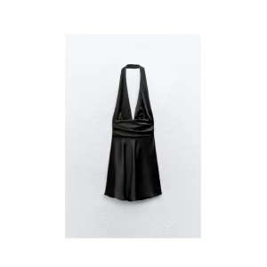 Svart halterneck klänning - Snygg svart halterneck klänning i satin med djup v-ringning. Perfekt för en kväll ute eller en speciell tillställning. Den korta längden ger en chic och modern look.