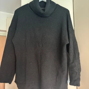 Svart stickad polotröja från Lager157 - Säljer en stilren svart stickad polotröja från Lager157. Tröjan har en hög polokrage och långa ärmar, perfekt för kyliga dagar. Den är mjuk och bekväm, idealisk för både vardag och mer uppklädda tillfällen.