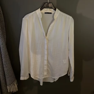 Vit blus från 157 - Säljer en stilren vit blus från lager 157. Blusen har långa ärmar och en klassisk krage med knappar framtill. Perfekt för en elegant och avslappnad look. Väldigt fin bakifrån