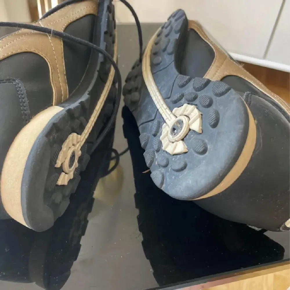 Snygga svarta sneakers från Elite med beige detaljer och snörning. Skorna har en rund tå och en unik sula med mönster för extra grepp. Perfekta för en stilren look.. Kengät.