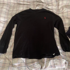 Ralph Lauren tröja - Säljer en stilren svart tröja från Ralph Lauren med det klassiska röda logotypen på bröstet. Perfekt för en avslappnad men ändå snygg look. Sitter som M. Pris kan diskuteras 