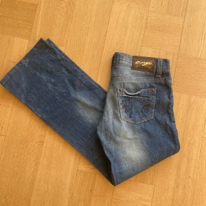 Lågmidjade Blå jeans  - Snygga blå jeans med broderade detaljer på bakfickan. Utsvängda och Lågmidjade💕 midjemått rakt över är 39cm och innerbenslängd är 74cm. Storlek 29/32
