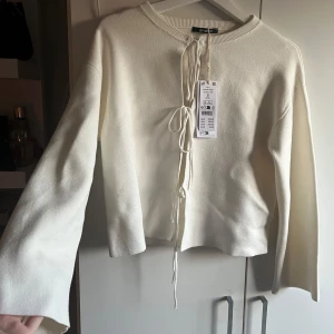 Vit ny tröja med knutar från Gina Tricot - Säljer en stilren vit tröja från Gina Tricot. Tröjan har långa ärmar och en snygg knytning framtill som ger en unik touch. Köpte för ett tag sen men har tyvärr inte kommit till användning, går att förhandla.
