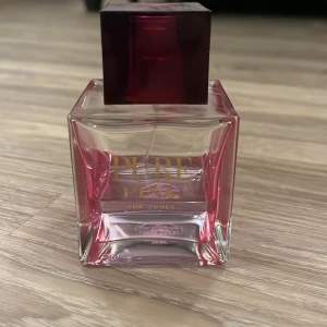 Pure Pink by Karen Low  Eau de Parfum - Säljer en elegant flaska Pure Pink Eau de Parfum från Greatest. Flaskan är fyrkantig med en rosa ton och har en mörkrosa fyrkantig kork.  100 ml flaska varav nästan hälften är kvar. En fräsch och feminin doft. 