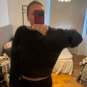 Svart fluffig tröja med öppen rygg - säljer denna superfina lite festligare stickade tröja med öppen rygg. som ni ser på sista bilden så är den lite glittrig (typ), skriv om ni har några funderingar!