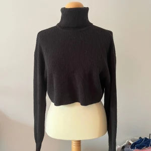 Svart ribbad polotröja - Snygg svart ribbad polotröja med hög krage och långa ärmar. Perfekt för kyligare dagar och ger en stilren look. Passar bra till både jeans och kjol.