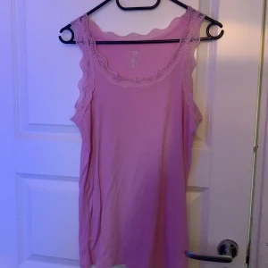 Rosa ärmlös topp från VRS - Säljer en söt rosa ärmlös topp från VRS med spetsdetaljer runt halsringningen och ärmhålen. Finns en exakt samma i lila. Perfekt för en avslappnad och feminin look. 💖Båda för 50kr