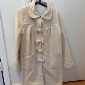 kappa med rosetter - Gullig kappa med söta rosettknäppningar framtill och en dekorativ rosett på baksidan. Den har långa ärmar och två fickor framtill. Säljer då den är lite för lite för mig. 