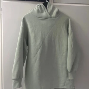 Ljusgrön lång hoodie från 157 XS /S - Säljer en ljusgrön lång hoodie från 157. Den har en klassisk design med långa ärmar och en bekväm huva. Slits på vänster sida med dragsko. Storlek XS-S