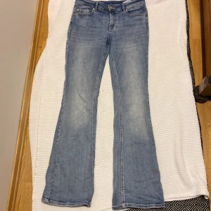 Ljusblå bootcut jeans från Vero Moda L/32 - Säljer ett par ljusblå jeans från Vero Moda med klassisk femficksdesign och bootcut-ben. Jeansen har normal passform och stängs med knapp och dragkedja. Perfekta för dig som gillar en avslappnad och tidlös stil.