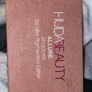 Huda Beauty Allure ögonskuggspalett - Säljer denna superfina Huda Beauty Allure Glitter Palette med 24 ultra-pigmenterade glitterfärger! Perfekt för dig som älskar glam, fester, festivaler eller kreativa looks. Paletten är i nyskick, Alla färger är intensiva, skimrande och sitter länge på huden. Nypris 600