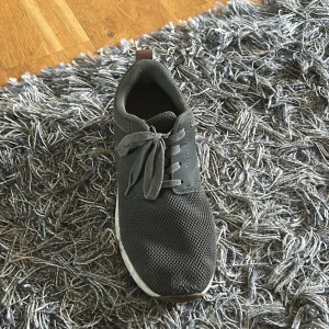 Mörkgröna sneakers med snörning - Säljer ett par mörkgröna sneakers med snörning och mesh-överdel. Skorna har en vit sula och detaljer i brunt på hälen. Perfekta för vardagsbruk och har en sportig look. Fråga gärna frågor 
