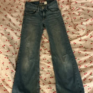 Blå bootcut jeans från H&M - Säljer ett par klassiska blå bootcut jeans från H&M. Jeansen har normal passform, fem fickor och stängs med dragkedja och knapp. Perfekta för dig som gillar en tidlös denimlook.