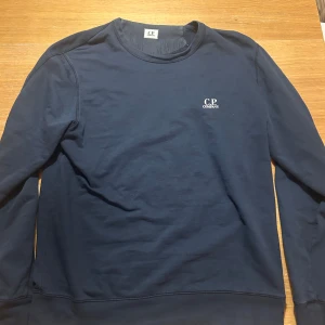 Mörkblå sweatshirt från C.P. Company - Säljer en sjukt snygg mörkblå sweatshirt från C.P. Company i mjuk bomull. Perfekt för en avslappnad och snygg look. Vid frågor eller funderingar är det bara att höra av sig! RIKTIG STEAL‼️slutsåld överallt! Byten kan vara intressant!