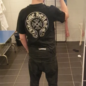 Svart t-shirt från Chrome Hearts - Säljer en svart t-shirt från Chrome Hearts med stort tryck på ryggen och mindre logga på bröstet. T-shirten har rund hals och korta ärmar. Perfekt för dig som gillar streetwear och vill sticka ut med en ikonisk design.