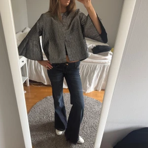 Silvrig croppad jacka med vida ärmar - Säljer en silvrig jacka med croppad passform och vida, trekvartsärmar. Jackan har en lätt glittrig yta och rak form utan synliga knappar eller dragkedja. Aldrig använd med prislappen kvar, nypris 599kr🩶 
