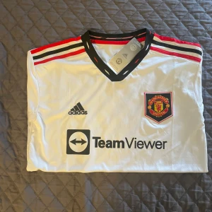 Manchester United bortatröja 2022/23 - Vit Manchester United bortatröja från Adidas med svarta och röda detaljer. Strl är S men den är ganska stor i storlek, passar därför som M.