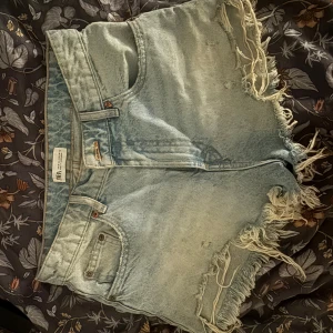 Ljusblå jeansshorts med fransar från Zara - Säljer ett par ljusblå jeansshorts från Zara. Storlek 38 men små i storleken💕
