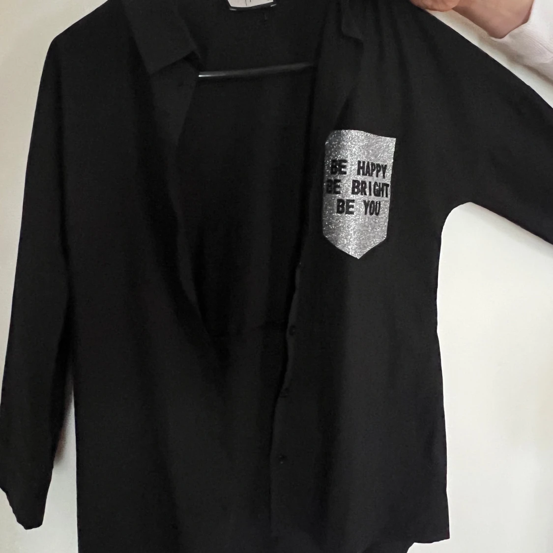 Svart skjortjacka med glittrig text från Saga - 2