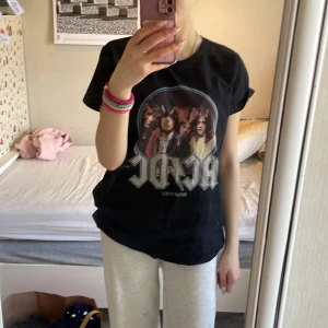 Svart AC/DC t-shirt med tryck - 35kr Svart t-shirt med stort AC/DC-tryck och motiv från 'Highway to Hell' på framsidan. Klassisk rund hals och korta ärmar. Perfekt för dig som gillar bandtröjor och vill ha en cool och avslappnad stil.