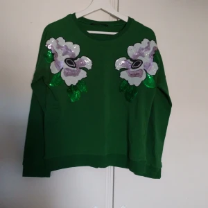 Grön sweatshirt med paljettblommor😊 - Hej, Säljer en jätte fin grön sweatshirt från Fornarina med stora blommor i paljetter vid axlarna. Perfekt för dig som vill sticka ut med lite extra glitter och färg.💕