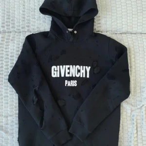 Givenchy hoodie  - Säljer en svart hoodie från Givenchy Paris med vit logga på bröstet. Tröjan har slitna detaljer och är tillverkad i bomull med polyesterfoder i huvan. Klassisk passform med långa ärmar och huva. Fraktas endast ! 
