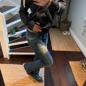 Låg midjade bootcut jeans från Lee - Säljer mina snygg låg midjade, bootcut Lee jeans. Har väldigt små defekter längs ner vid kanten annars är dem i perfekt skick. Snygga knappar på fickorna med rosa sömmar som detalj. Fråga gärna om bilder eller funderingar:) 