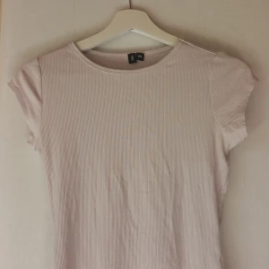 Ljusrosa ribbad t-shirt från Lager 157 - Säljer en ljusrosa ribbad t-shirt från Kager 157. T-shirten har rund halsringning och korta ärmar. Perfekt basplagg i garderoben och superenkel att matcha med olika outfits.