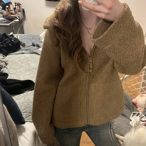 Beige/brun teddyjacka med dragkedja - Mysig beige/brun teddyjacka med dragkedja framtill och hög krage. Jackan har en oversized passform och är tillverkad i ett mjukt, fluffigt teddy-material. köpt för 300kr.