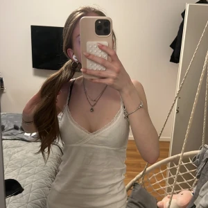 Vit spetskantad linnetopp från Brandy Melville - Säljer en vit linnetopp från Brandy Melville med smala axelband och fina spetsdetaljer längs kanterna. Köpt för 200kr