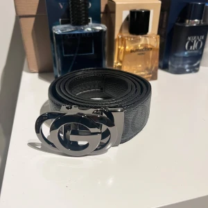 Svart bälte med silverfärgat spänne - Säljer ett svart bälte med ett stort, blankt silverfärgat spänne. Bältet är gjort i skinn och har en klassisk, stilren design som passar till många olika outfits. Helt nytt aldrig använt. Det är justerbart så man kan ändra så tajt eller löst man vill!