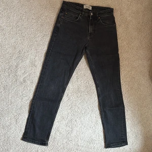 Svarta jeans från Pull&Bear - Säljer ett par svarta jeansbyxor från Pull&Bear med klassisk femficksdesign och raka ben. Jeansen har normal passform och är tillverkade i denim med snygg tvättad look. Perfekta för dig som gillar en enkel och stilren stil.