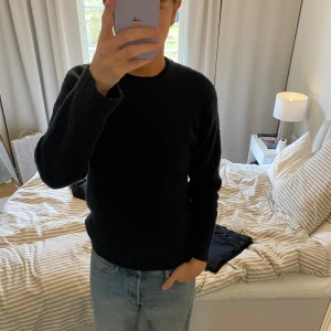 Mörkblå stickad tröja från Zara - Säljer en mörkblå stickad tröja från Zara med rund halsringning och långa ärmar. Tröjan har en enkel och klassisk design med ribbade muddar vid ärmslut och nederkant. Perfekt för kyligare dagar.